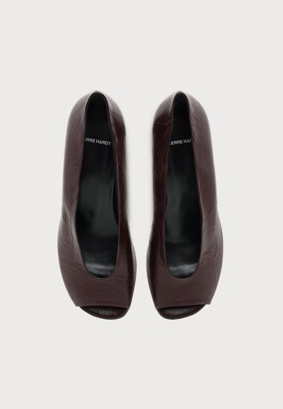 Ζεύγος καφέ δερμάτινα παπούτσια peep-toe με λεία, ελαφρώς ρυτιδιασμένη υφή και μαύρα πέλματα με την ετικέτα Pierre Hardy.