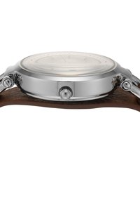 Montre en acier inoxydable avec un cadran en verre clair, bracelet en cuir brun, forme ronde et deux boutons latéraux pour les réglages.