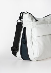 Borsa bianca in materiale testurizzato, con tracolla nera e accessori in metallo. Comprende una tasca con zip e una chiusura a pattina. Forma rettangolare.