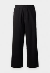 Schwarze Jogginghose mit elastischem Bund, entspannter Passform, geraden Beinen und ohne sichtbare Muster oder Hardware. Weiche Textur, lässiges Design.