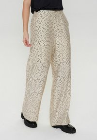 Beige wijde broek met zwarte stippen, met een ontspannen pasvorm en gestructureerde stof, ontworpen met zijzakken en een hoge taille.