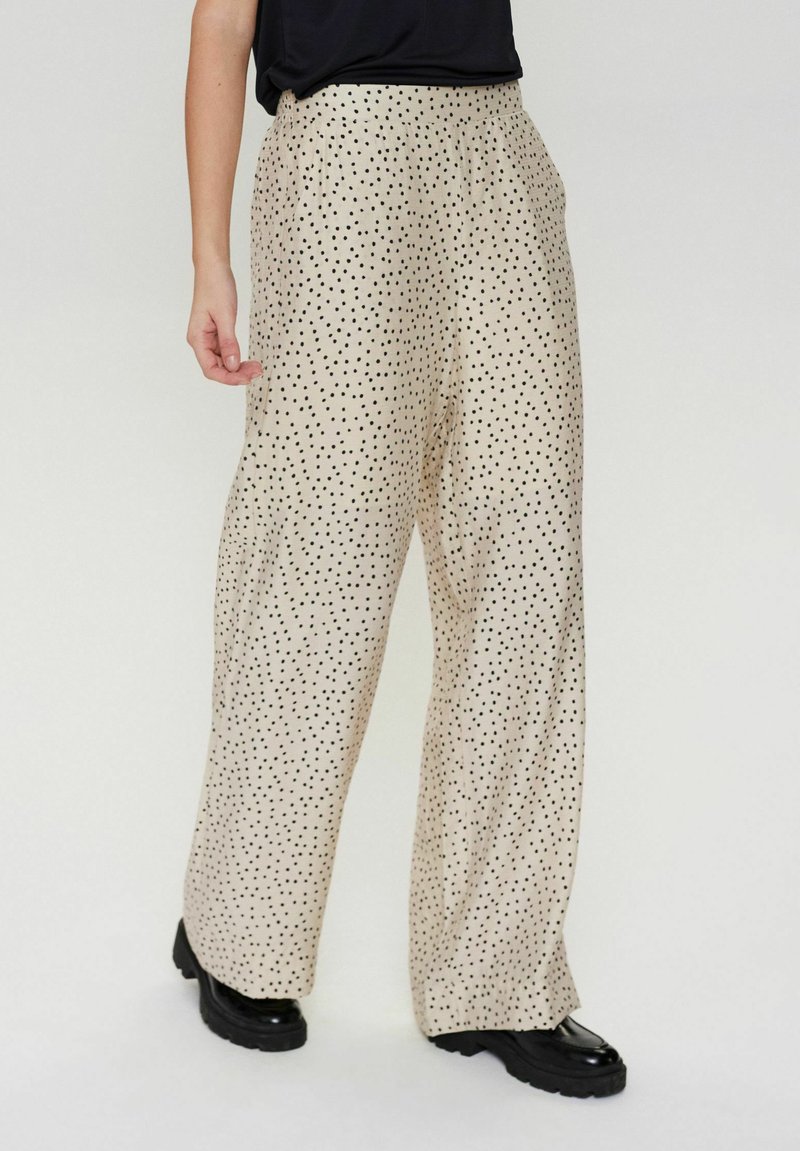 Beige wijde broek met zwarte stippen, met een ontspannen pasvorm en gestructureerde stof, ontworpen met zijzakken en een hoge taille.