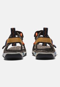 Sandalias marrones y grises con correas ajustables, que presentan acentos en naranja y azul, suela texturada y bucles en el talón trasero para un fácil calzado.