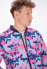 Giacca bomber colorata con un motivo camouflage nei colori rosa, blu e navy, dotata di zip frontale e colletto a coste.
