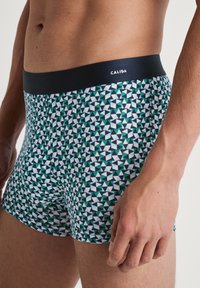 Calida boxers met een geometrisch patroon in teal, wit en marineblauw, met een donkere tailleband. Gemaakt van zacht, rekbaar materiaal.