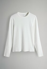 Weißes Langarmshirt mit geripptem Muster, Rundhalsausschnitt und seitlichen Schlitzen am Saum. Hergestellt aus einem weichen, leichten Stoff.