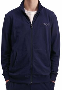 Giacca zip-up blu navy realizzata in misto cotone, con colletto alto, due tasche frontali e stampa logo grigia sul lato sinistro del petto.