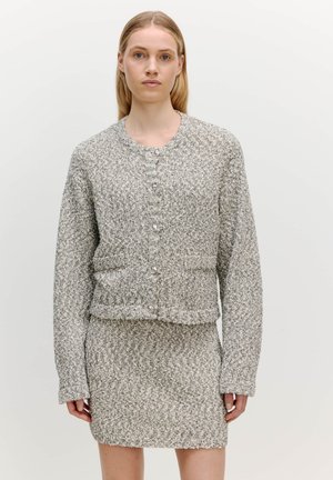 Cardigan tricot gris et blanc texturé avec col rond et manches longues, doté d'une fermeture à boutons sur le devant et d'une jupe tricot assortie.