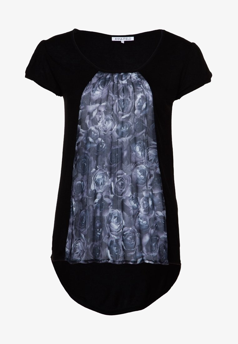 Blouse noire à manches courtes avec un panneau plissé à motifs floraux gris à l'avant. Encolure arrondie et ourlet incurvé à l'arrière. Texture de tissu douce.