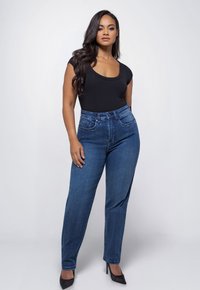 Zwarte bodysuit met ronde hals, gecombineerd met high-waisted, rechte spijkerbroeken in blauw. De spijkerbroeken hebben een vijf-pocket stijl en een klassieke dennen textuur.