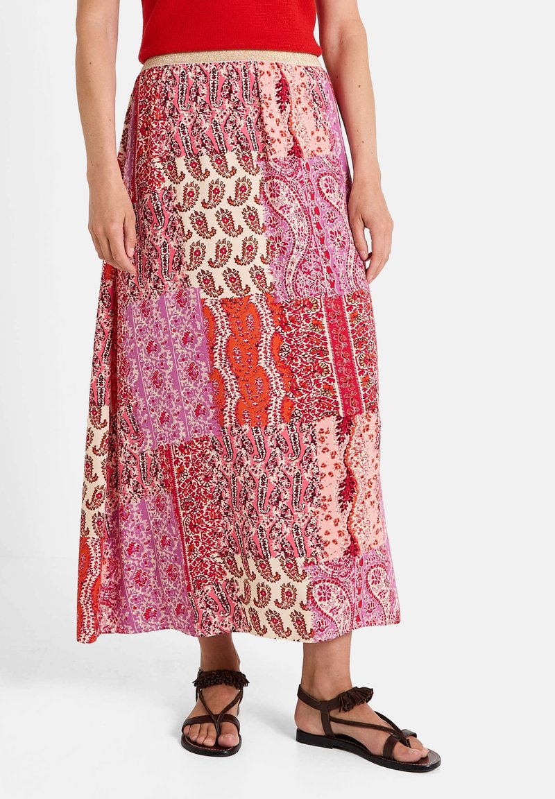 Falda maxi con un diseño de patchwork en rosa, rojo y crema, que presenta patrones florales y de paisley; cinturilla elástica y textura fluida.