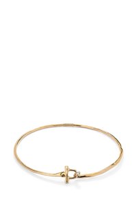 Pulsera bangle de metal dorado con un diseño suave y curvado, que cuenta con un cierre toggle sencillo y un pequeño acento de gema clara.
