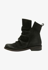 Botín negro hasta el tobillo con parte superior de cuero texturizado y perforado, diseño holgado, tacón de madera bajo y una lengüeta en la parte posterior para una fácil puesta.