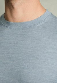 Világoskék, rövid ujjú póló, puha, bordás anyagból készült, kerek kivágással és látható minták vagy grafikák nélkül.