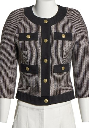 Veste courte à motif noir et blanc avec manches trois-quarts, bordure noire, quatre poches avant et fermetures par boutons dorés.
