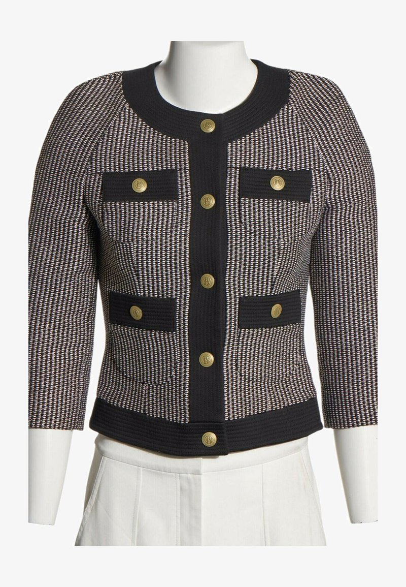 Veste courte à motif noir et blanc avec manches trois-quarts, bordure noire, quatre poches avant et fermetures par boutons dorés.