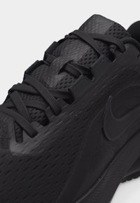 Μαύρο αθλητικό παπούτσι με επάνω μέρος από υφασμάτινο πλέγμα με υφή, μαύρα κορδόνια και λογότυπο Nike Swoosh στο πλάι.