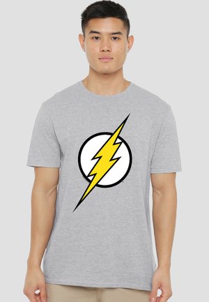 Young man wearing a light gray t-shirt with a large yellow lightning bolt inside a black-outlined white circle on the chest.