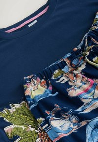 Haut bleu marine avec feuilles vertes brodées, associé à un pantalon bleu marine à taille élastique avec des animaux illustrés colorés et des scènes de jungle.