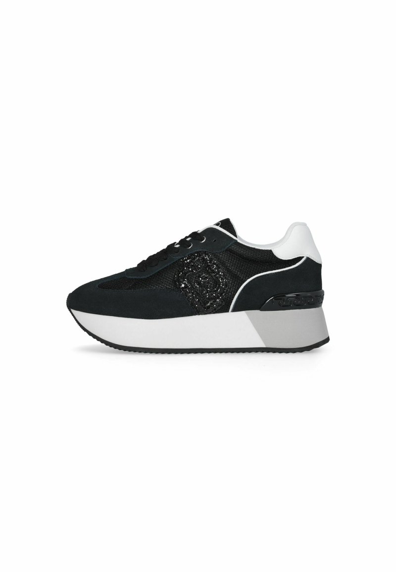 Zapatilla negra con materiales de malla y ante, un diseño texturizado en negro, acentos en blanco y una suela gruesa con un talón con patrón.