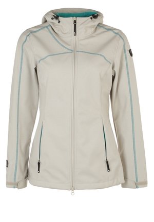 Mujer con chaqueta con capucha gris claro, camisa blanca, pantalones azul marino y botas de senderismo negras, de pie con un pie ligeramente levantado.