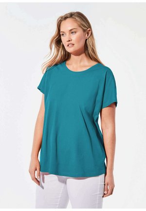 Teal T-shirt met korte mouwen en een ronde halslijn, met een losse pasvorm en een gladde katoentextuur, gecombineerd met witte broek.
