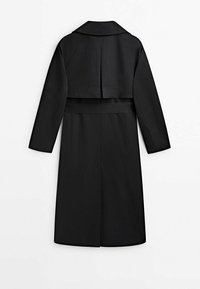 Mustassa trench-takissa on pitkät hihat, lovettu kaulus ja vyötärölle sidottu vyö. Suunnittelussa on selkälaikku ja suora helma.