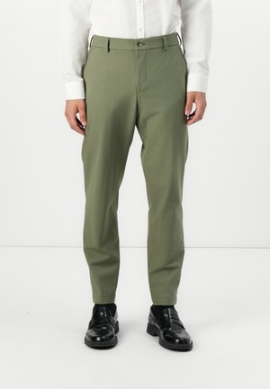 Green, tapered trousers made of a textured fabric. Features a front button closure and side pockets. Worn with black dress shoes.