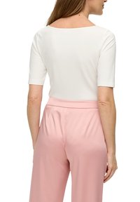 Witte korte mouwen top met een vierkante halslijn, gecombineerd met lichtroze op maat gemaakte broek. Gladde textuur, aansluitend ontwerp en minimale details.