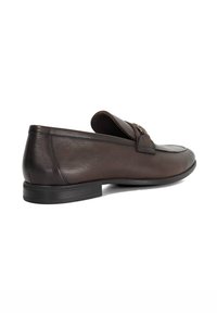 Brown leather loafers with a low profile, round toe, and decorative stitching. Features a flat rubber sole and metal accent on the upper.