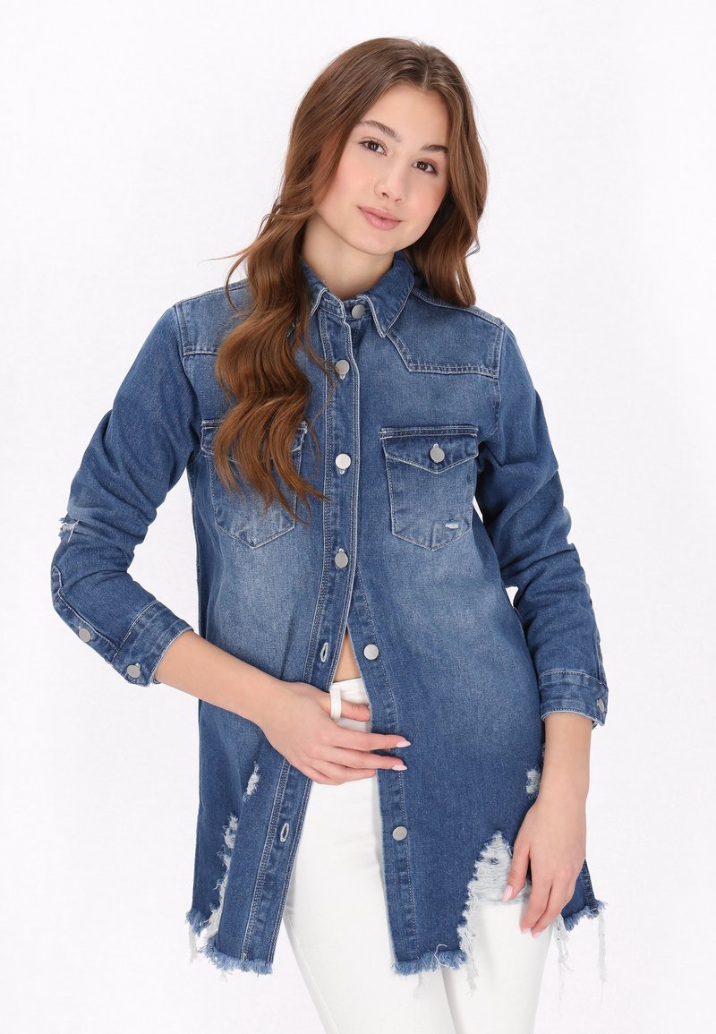 Denim overhemd in donkerblauw met lange mouwen, drukknoopsluitingen, puntige kraag en twee borstzakken; met een rafelige zoom en versleten details.
