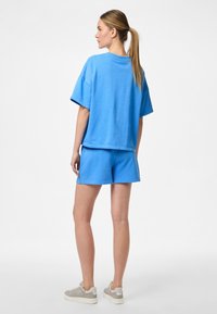 T-shirt en coton oversize bleu ciel et short assorti, avec des manches courtes et une coupe décontractée, associés à des baskets gris clair.
