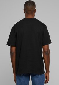 Black cotton T-shirt featuring a relaxed fit, short sleeves, and a crew neckline, displayed from the back with a plain design.