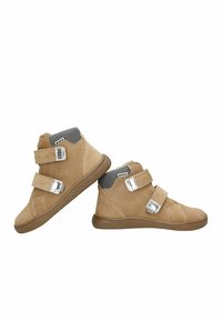 Des bottines en suède beige à la cheville affichent deux bandes Velcro, un col en maille grise, et une semelle en caoutchouc texturée avec de subtils détails de couture.