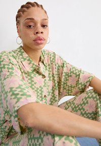 Groen en roze patroonkleding met korte mouwen; losse pasvorm, met een subtiel golfpatroon en bloemenaccenten, gemaakt van zachte stof.