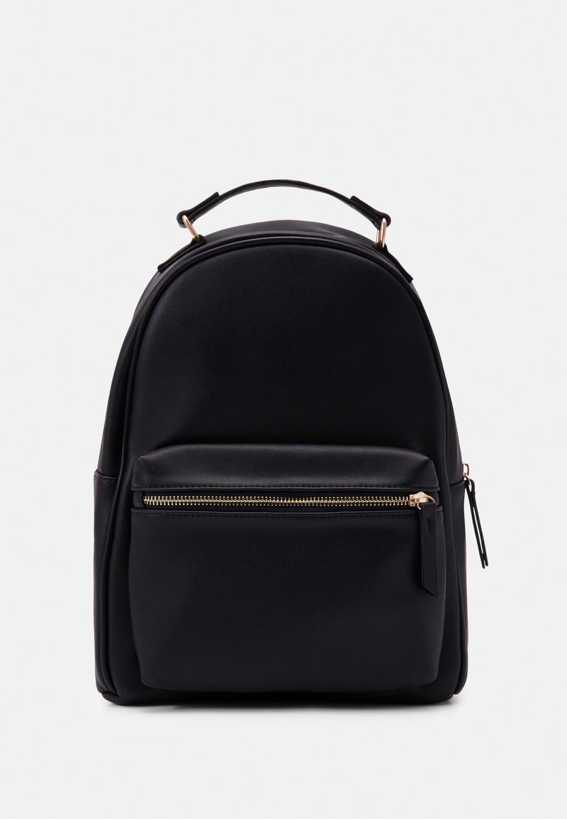 Sac à dos noir avec une poignée supérieure, une poche avant zippée avec une fermeture éclair dorée et un matériau lisse sur fond blanc uni.