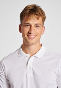 Hvid polo skjorte med en krave med to knapper, korte ærmer og et diskret tekstureret stof. Modellen præsenterer en neutral baggrund.