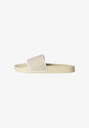 Cream slide sandal with a wide strap featuring a subtle embossed logo pattern. Soft rubber sole and branded detail on the side.