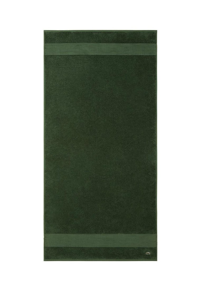 Toalla rectangular de color verde oscuro con dos rayas horizontales texturizadas cerca de los bordes y un pequeño logotipo de cocodrilo bordado en una esquina.