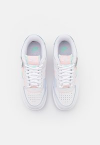 Bijele tenisice s kožnom gornjom djelom, pastelno ružičastim i mentol zelenim detaljima, perforiranim prednjim dijelom i vezanjem. Nike brendiranje vidljivo.