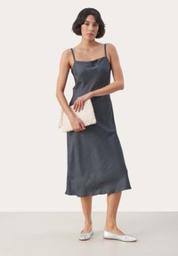 Rochie slip din satin gri închis, cu bretele subțiri, până la genunchi, dintr-un material texturat. Asortată cu o poșetă împletită bej și balerini argintii.