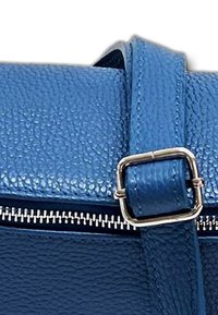 Blauwe leren handtas met textuur, voorzien van een zilveren rits, met een rechthoekige gespstrand en zichtbare stiksels.