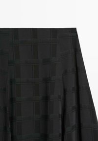 Tessuto nero con un sottile motivo a quadri. La texture è liscia, con diverse sfumature che creano un effetto di profondità. I bordi sono rifiniti con precisione.