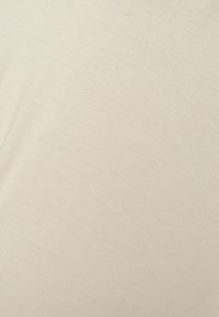 Tecido bege com uma textura suave, apresentando um ligeiro brilho e variações subtis no tom. O material parece leve e respirável.