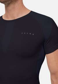 Czarna sportowa koszulka z gładkiego, elastycznego materiału. Posiada okrągły dekolt, krótkie rękawy oraz prążkowane akcenty na ramionach. Logo w kolorze białym.