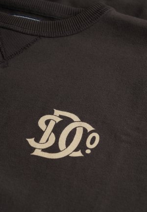 Brown sweatshirt featuring a prominent beige "D0" logo, ribbed neckline, and smooth fabric texture.