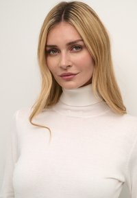 Pulover alb, cu guler înalt, mulat, dintr-un material moale, având o textură fină și mâneci lungi, cu accente subtile striate la guler.