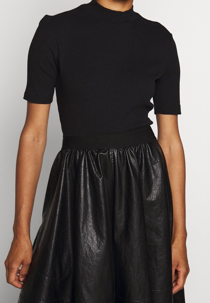 Czarny prążkowany top z krótkim rękawem i stójką, połączony z czarną błyszczącą spódnicą z faux skórki, z marszczonym pasem i kieszeniami.