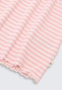 Różowo-biały, poziomo prążkowany materiał z falbanką na krawędzi i małą białą metką na jasnoszarym tle.