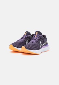 Zapatillas deportivas en morado y gris con una parte superior de malla texturizada, acentos en naranja, una entresuela blanca y una suela de goma. Detalles de diseño llamativos.